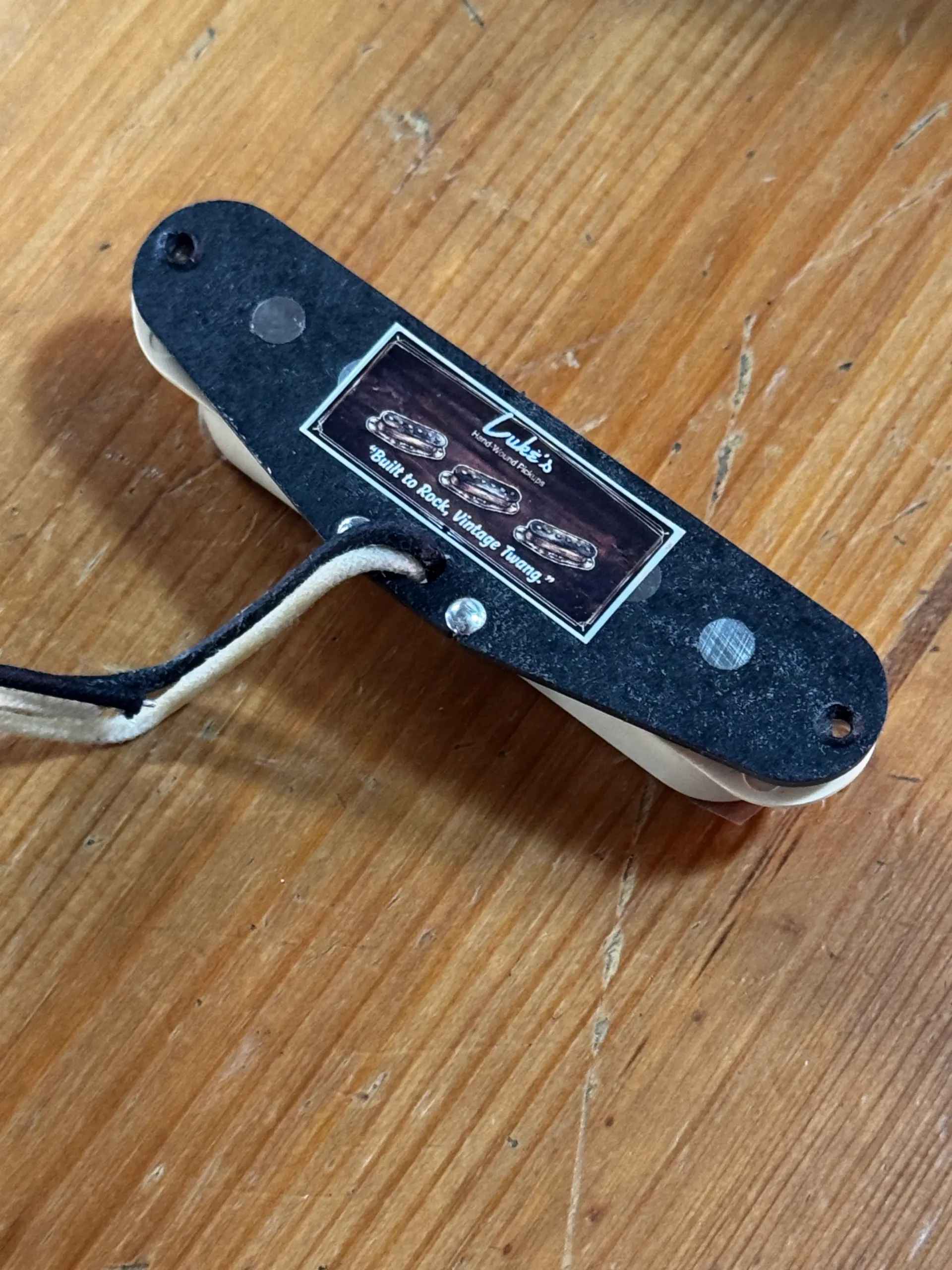 Hand-wound single-coil pickup resting on a wooden workbench