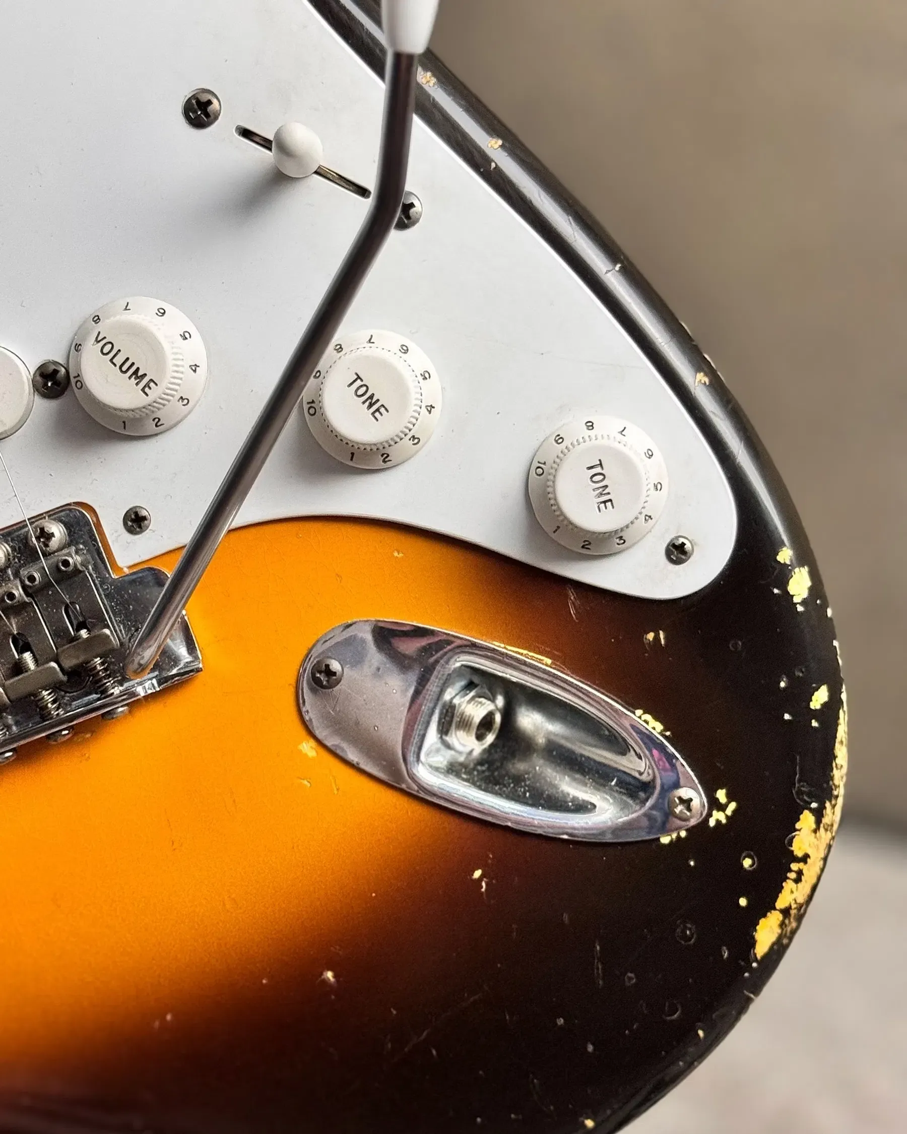 Close detail of an aged sunburst guitar finish and tremolo bridge